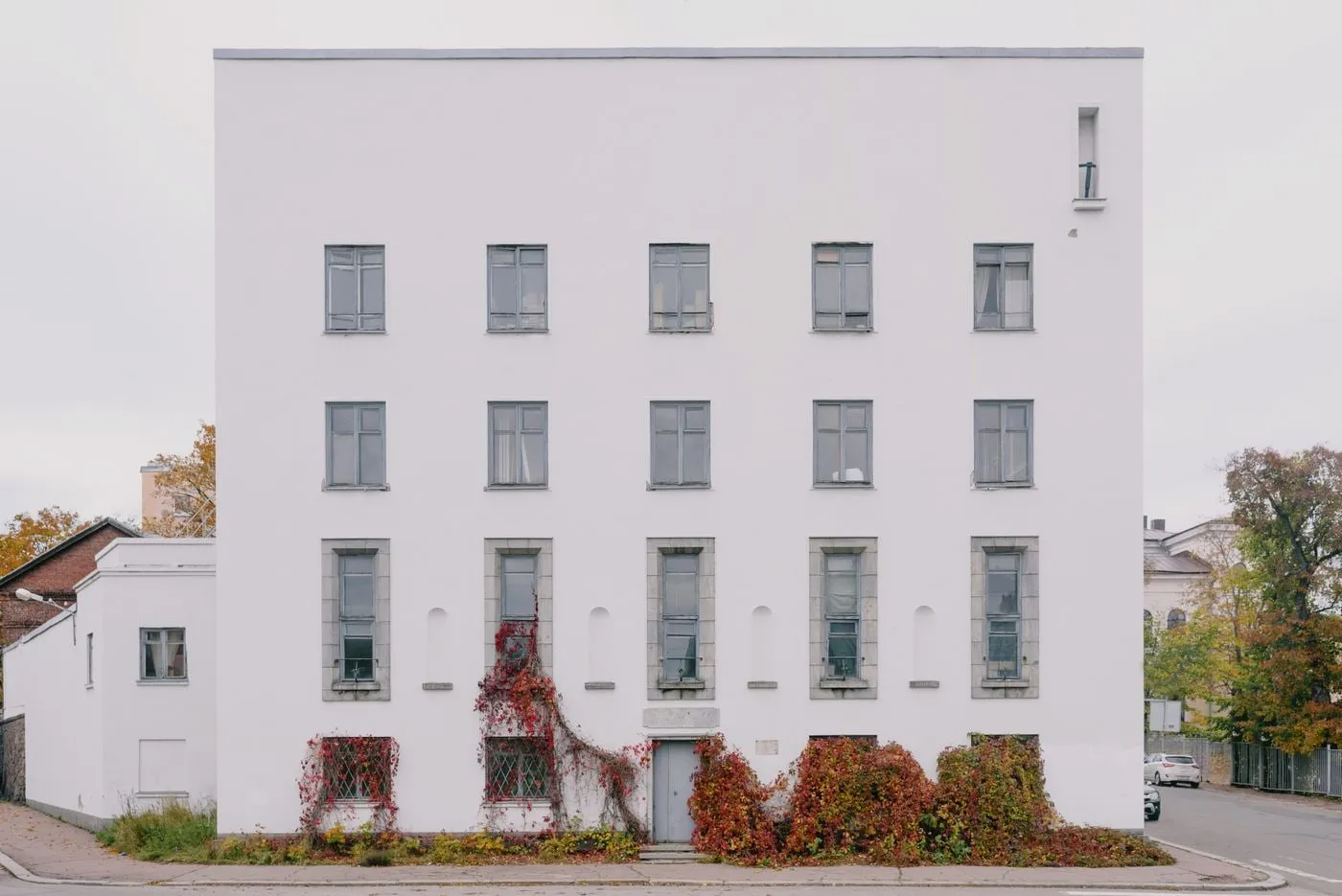 Fachada de un edificio residencial blanco con vegetación en la planta baja