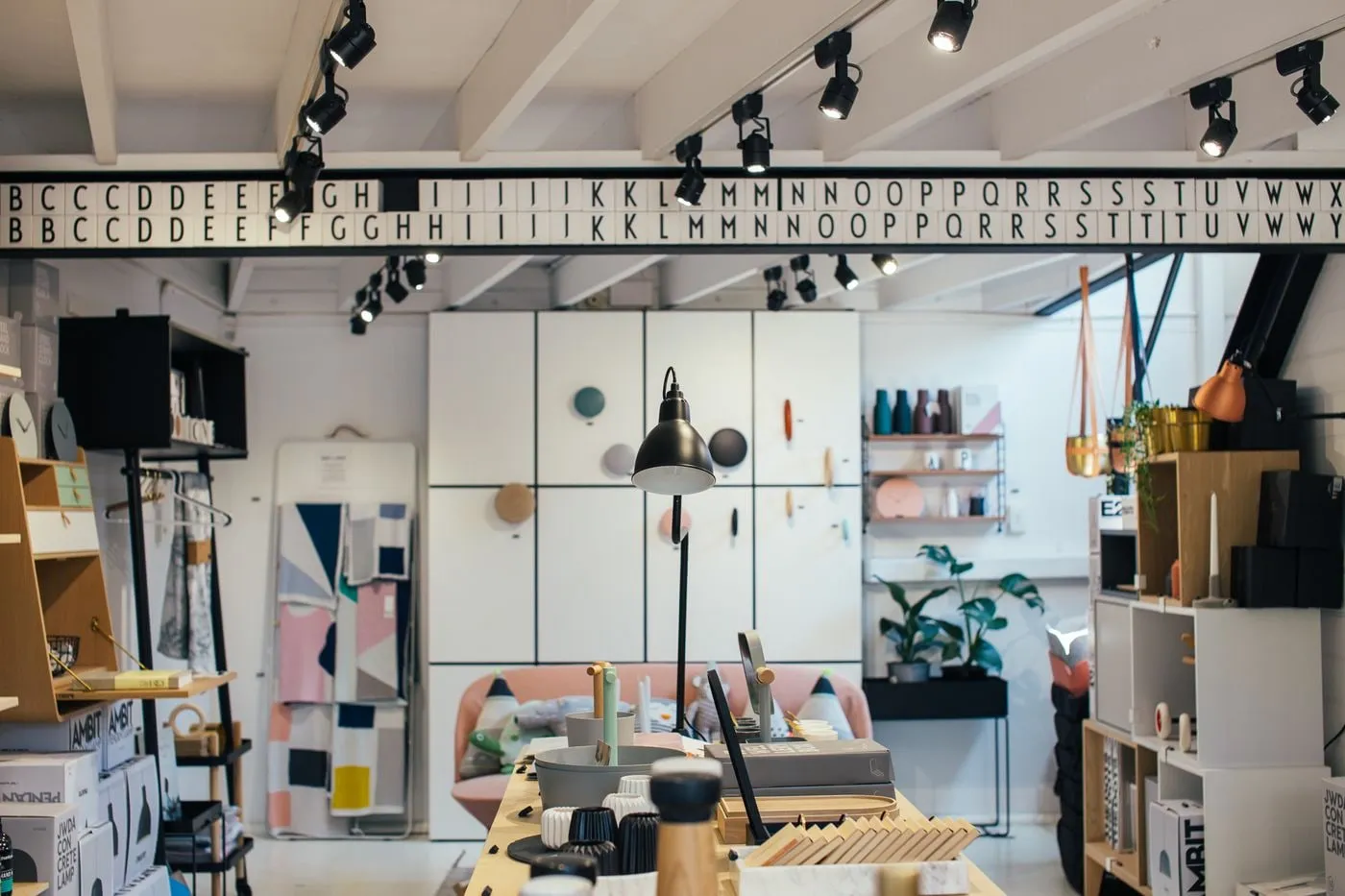 Interior de local comercial con estanterías, iluminación de raíl y plantas