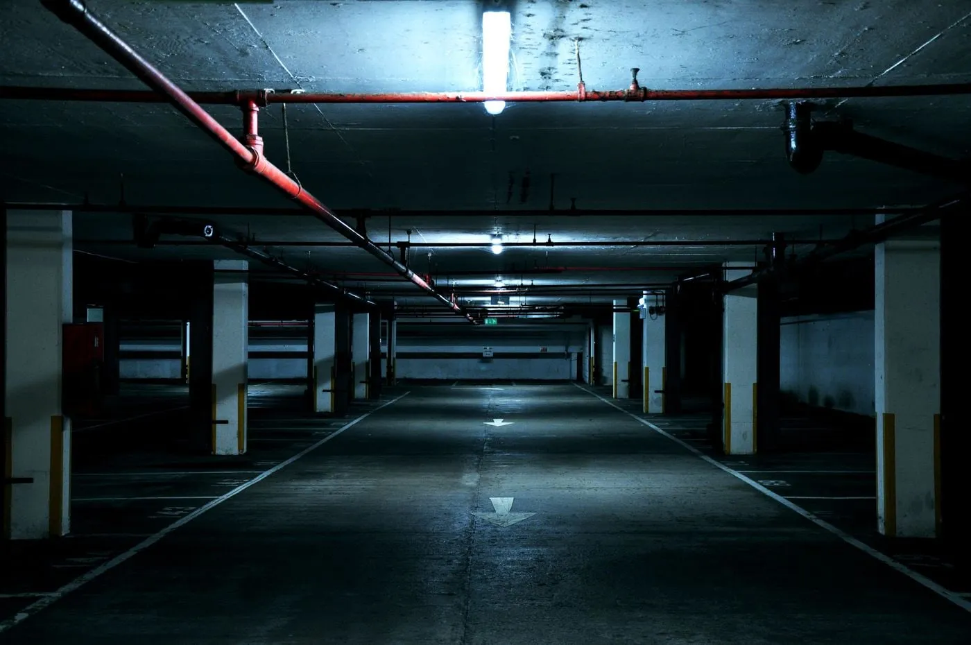 Parking subterráneo vacío con pilares de hormigón e iluminación lineal