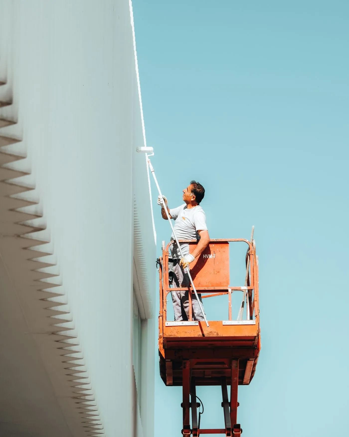 Operario pintando la fachada de un edificio desde una plataforma elevadora