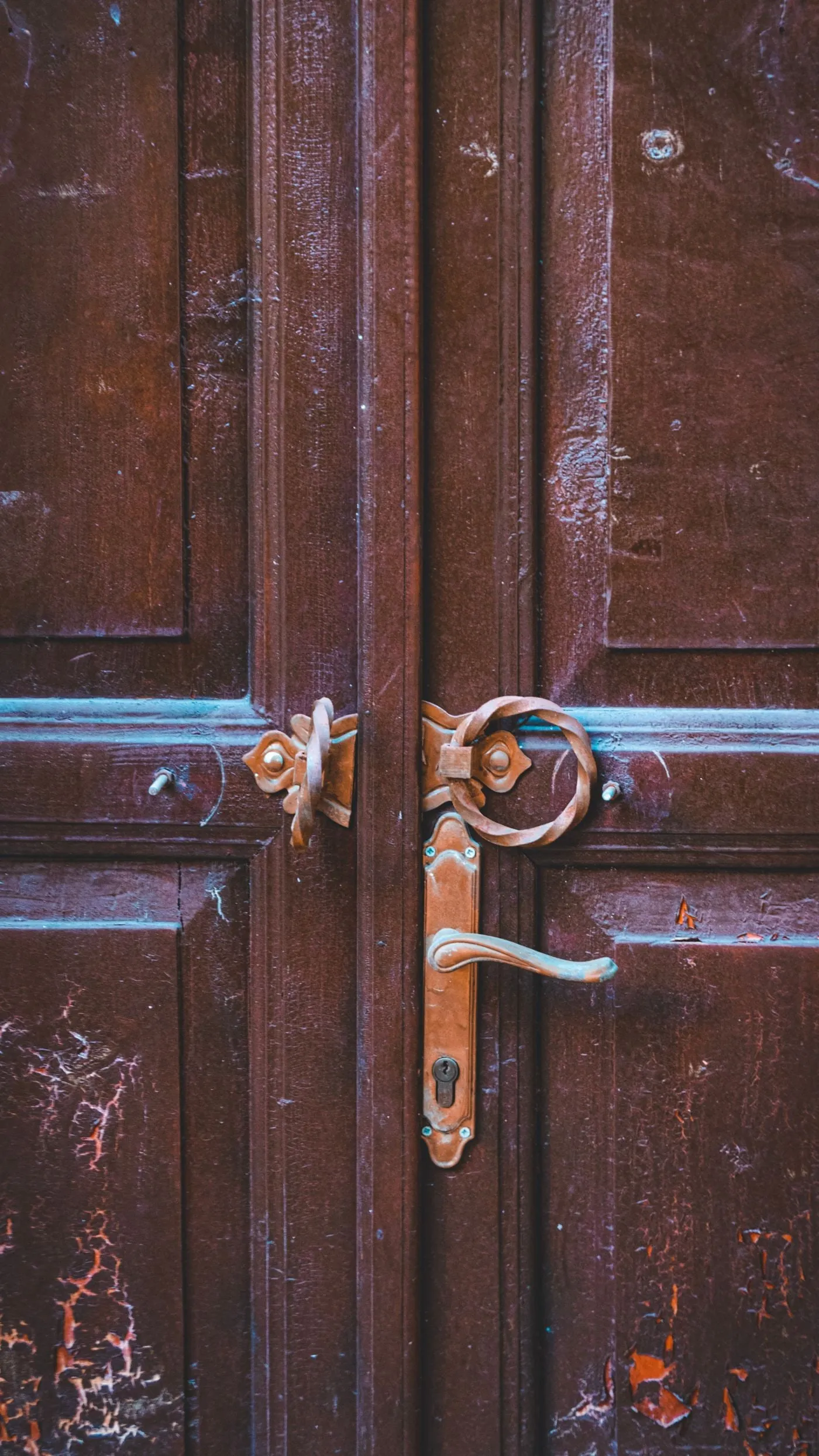 Puerta de madera antigua con pintura turquesa y herrajes desgastados